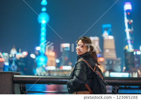 woman traveler visiting in Shanghai, China. Happy Female Tourist sightseeing Shanghai view of Lujiazui in The Bund of Shanghai at night. landmark and popular for tourism attractions. Vacation concept 123065288