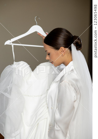 Bride holding wedding dress on hanger smiling Bride holding wedding dress on hanger smiling 123065498