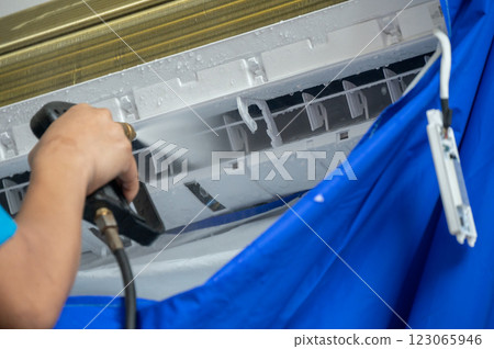 Cropped shot view of technician spraying high pressure water for cleaning air conditioner filter. Spraying water on your air conditioner to clear dirt and other debris. 123065946