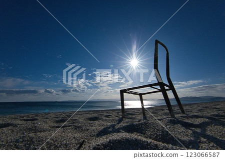 The sun shines brightly on an iron chair abandoned on the beach. The sun shines brightly on an iron chair abandoned on the beach. 123066587
