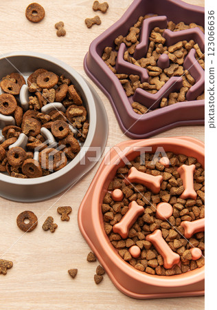 Slow feeder dog bowls with various dry food on wooden table Slow feeder dog bowls with various dry food on wooden table 123066636