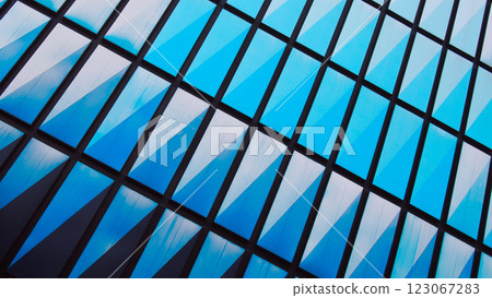Geometric Reflections. An abstract close-up of a modern glass building facade, featuring a striking pattern of diagonal blue reflections framed by a black grid structure Geometric Reflections. An abstract close-up of a modern glass building facade, featuring a striking pattern of diagonal blue reflections framed by a black grid structure 123067283
