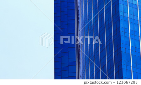 Minimalist Blue Glass Skyscrapers. Close-up of two modern high-rise buildings with reflective blue glass facades against a soft sky. 123067293