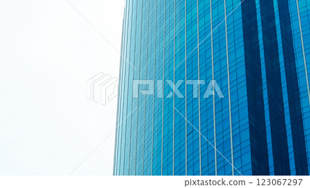 Modern Glass Skyscraper Architecture. Low-angle shot of a curved blue glass facade reflecting the sky and cityscape. Modern Glass Skyscraper Architecture. Low-angle shot of a curved blue glass facade reflecting the sky and cityscape. 123067297