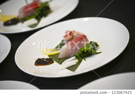 Delicate Japanese fish dish elegantly arranged with fresh greens, lemon, and a flavorful sauce on a Delicate Japanese fish dish elegantly arranged with fresh greens, lemon, and a flavorful sauce on a 123067425