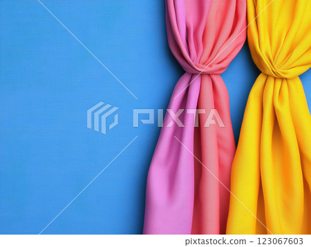 Vibrant pink and yellow fabric drapes against blue background, creating cheerful atmosphere 123067603