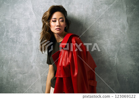 Fashionable confident woman wearing red coat and stylish casual outfit posing at studio. Fashionable confident woman wearing red coat and stylish casual outfit posing at studio. 123069122