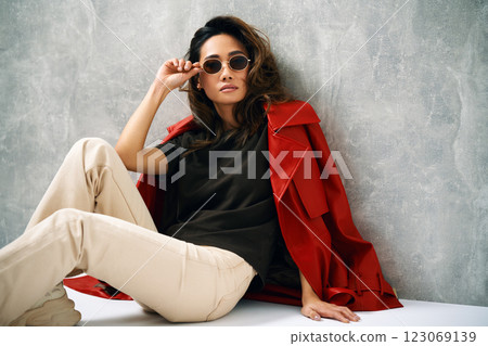 Fashionable confident woman wearing red coat and stylish casual outfit posing at studio. Fashionable confident woman wearing red coat and stylish casual outfit posing at studio. 123069139