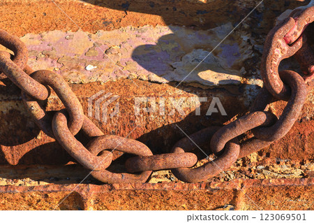 Rusty chain casting shadow on weathered surface 123069501