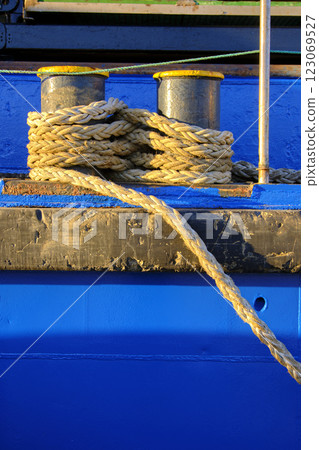 Nautical ropes tightly secured on blue vessel 123069527
