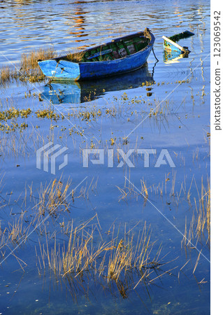 Abandoned blue rowboat resting in calm waters 123069542