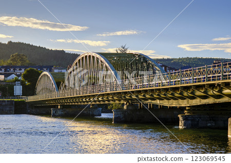 Arch bridge spanning over calm river waters 123069545