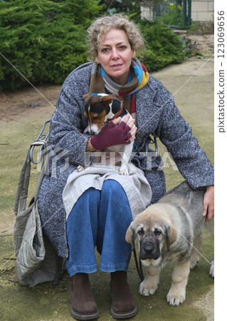 Woman hugging puppies sitting on chair outdoors Woman hugging puppies sitting on chair outdoors 123069656