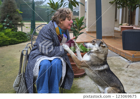 Czechoslovakian wolfdog giving paw to its owner sitting on a garden chair Czechoslovakian wolfdog giving paw to its owner sitting on a garden chair 123069675