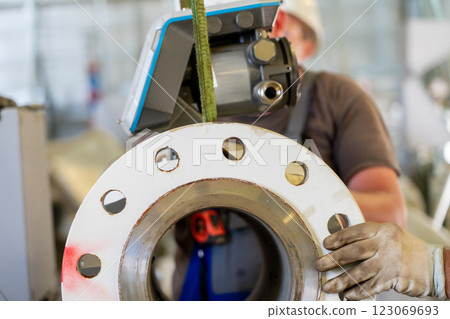 Worker handling an ultrasonic flow meter with a flanged connection during installation Worker handling an ultrasonic flow meter with a flanged connection during installation 123069693