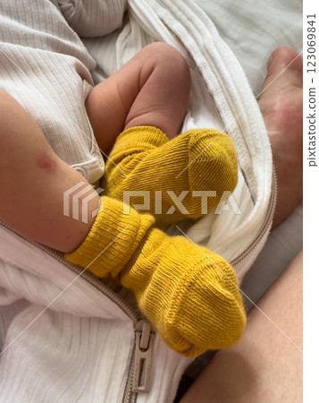 Baby in Yellow Socks Wrapped in White Blanket 123069841