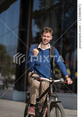 Portrait of a successful raising his arm in victory, celebrating success outside a modern office. 123069971