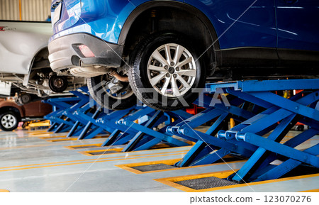 Car suspension maintenance during tire replacement at a garage workshop with professional mechanic performing repair and alignment services, ensuring vehicle safety and optimal performance. 123070276