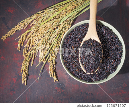Beautiful black-rice in a bowl with wooden spoon and ears of rice on table Beautiful black-rice in a bowl with wooden spoon and ears of rice on table 123071207