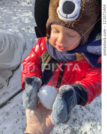 Little boy in red jacket, mittens and warm hat take snowball. Sunny day in winter. Snow and the seasons. Little boy in red jacket, mittens and warm hat take snowball. Sunny day in winter. Snow and the seasons. 123071404