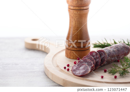 Matured salami on a cutting board with pink pepper and rosemary Matured salami on a cutting board with pink pepper and rosemary 123071447