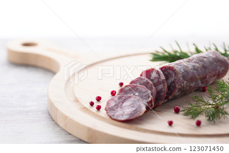 Matured salami on a cutting board with pink pepper and rosemary Matured salami on a cutting board with pink pepper and rosemary 123071450