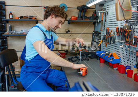 Professional repairman fixing angle grinder power tool at workshop Professional repairman fixing angle grinder power tool at workshop 123071729