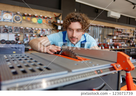 Construction worker choosing table circular saw while shopping at power tools shop Construction worker choosing table circular saw while shopping at power tools shop 123071739