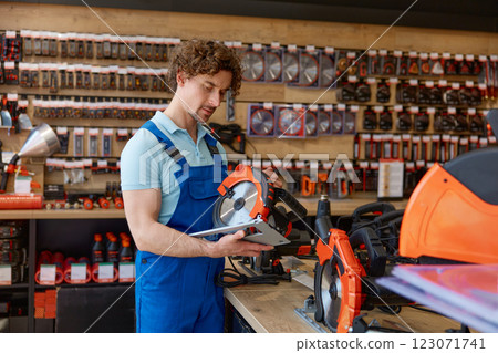 Closeup workman holding circular saw in hands choosing new electric tool 123071741