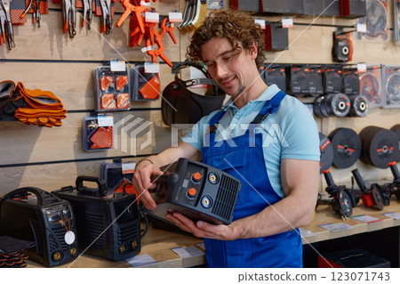 Man worker in overalls choosing welding machine at hardware store 123071743