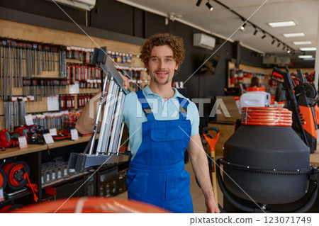Builder man buying steel ladder for high-rise works at hardware store 123071749