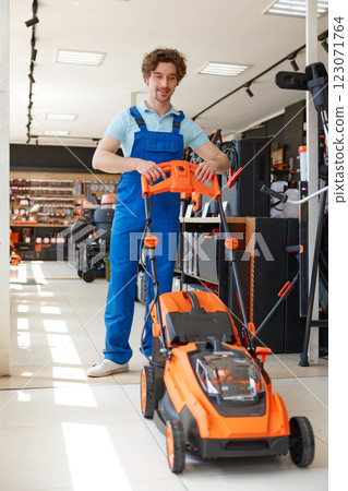Worker customer choosing electric lawnmower at garden supply store Worker customer choosing electric lawnmower at garden supply store 123071764