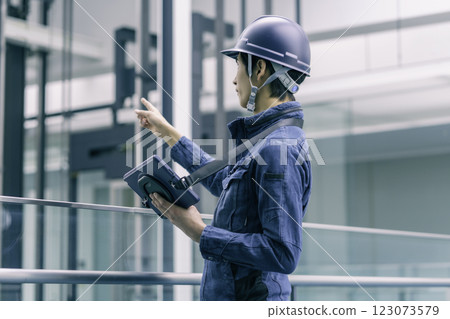 A young male worker at a construction site wearing a helmet and holding a tablet. Photo courtesy of Sky Perfect Tokyo Media Center. 123073579