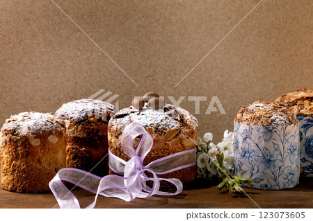 Homemade Italian traditional Easter panettone cakes in row, decorated by chocolate eggs, pink ribbon and blossoming cherry tree flowers standing on wooden table. Traditional Easter bake. Copy space Homemade Italian traditional Easter panettone cakes in row, decorated by chocolate eggs, pink ribbon and blossoming cherry tree flowers standing on wooden table. Traditional Easter bake. Copy space 123073605