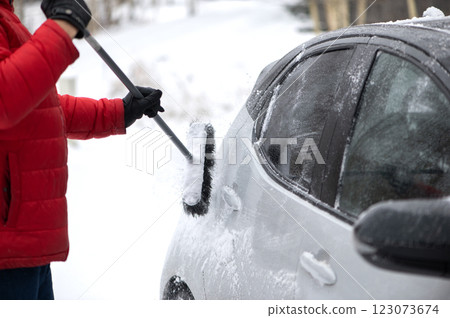 Man cleans the car from the snow with a brush. Bad snow weather concept. 123073674