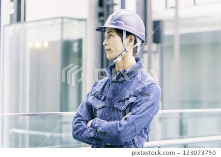 A young male worker wearing a helmet standing at a construction site. Photo courtesy of Sky Perfect Tokyo Media Center. 123073750