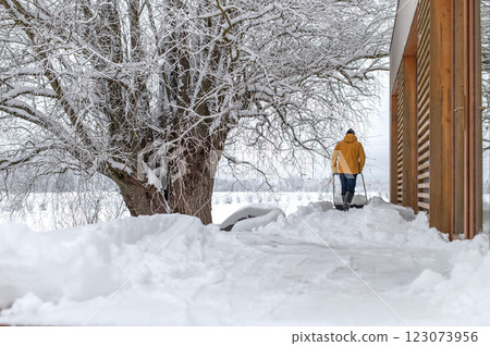 Rear view on man with snow shovel cleaning snow on terrace of the house 123073956