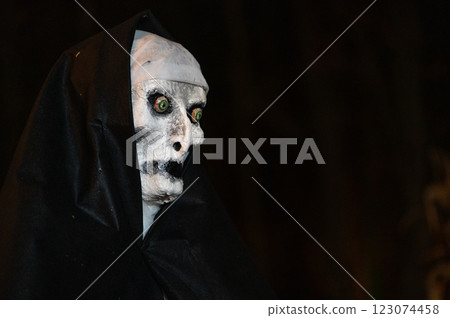 Scary Halloween witch with red eyes in a black cloak in a gloomy environment Scary Halloween witch with red eyes in a black cloak in a gloomy environment 123074458