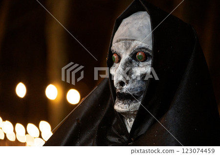 Scary Halloween witch with red eyes in a black cloak in a gloomy environment Scary Halloween witch with red eyes in a black cloak in a gloomy environment 123074459