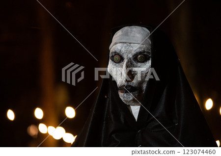 Scary Halloween witch with red eyes in a black cloak in a gloomy environment Scary Halloween witch with red eyes in a black cloak in a gloomy environment 123074460