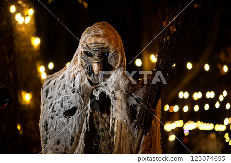 Witch with a broom and a monster face on a dark halloween horror night, bokeh light background Witch with a broom and a monster face on a dark halloween horror night, bokeh light background 123074695