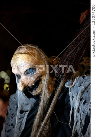 Witch with a broom and a monster face on a dark halloween horror night, bokeh light background 123074700
