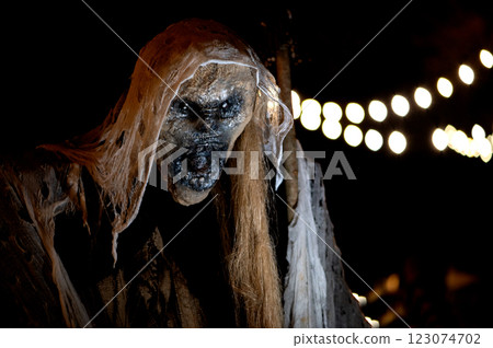 Witch with a broom and a monster face on a dark halloween horror night, bokeh light background 123074702