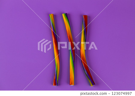 Vibrant Rainbow Candy Sticks on a Purple Background: A Colorful Treat Perfect for Celebrations and Sweet Tooth Indulgence 123074997
