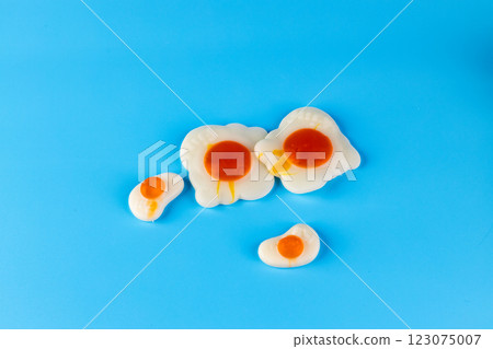 Creative Presentation of Colorful Fried Eggs on a Bright Blue Background, Showcasing Different Sizes and Styles of Egg Yolk and White, Perfect for Food or Culinary Themes 123075007