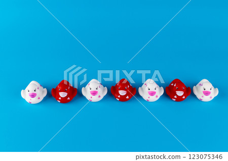 Colorful Collection of Cute Rubber Ducks: A Playful Display of Red and White Ducks Lined Up Against a Vivid Blue Background for Cheerful Decor and Fun Themes 123075346