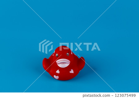 Charming and Playful Red Rubber Duck Featuring Delightful Heart Patterns on a Bright Blue Background for a Fun, Cheerful Atmosphere Charming and Playful Red Rubber Duck Featuring Delightful Heart Patterns on a Bright Blue Background for a Fun, Cheerful Atmosphere 123075499