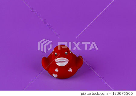 Charming Red Rubber Duck with Heart Patterns on Vibrant Purple Background: A Playful and Cute Addition to Any Bathroom Decor or Toy Collection for Children Charming Red Rubber Duck with Heart Patterns on Vibrant Purple Background: A Playful and Cute Addition to Any Bathroom Decor or Toy Collection for Children 123075500