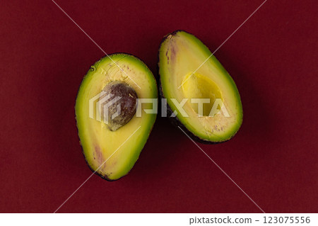 Vibrantly Split Avocado on a Bold Red Surface Showcasing its Creamy Texture and Rich Coloration Perfect for Culinary Inspiration and Healthy Eating Ideas 123075556