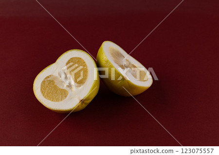 Vibrant Yellow Fruit Halves Displayed Against a Rich Maroon Background That Evoke Freshness and Zest in a Culinary Context, Perfect for Recipes and Nutritional Discussions 123075557